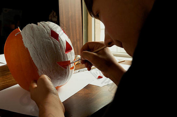 年轻的男孩雕刻绘画南瓜万圣节表格