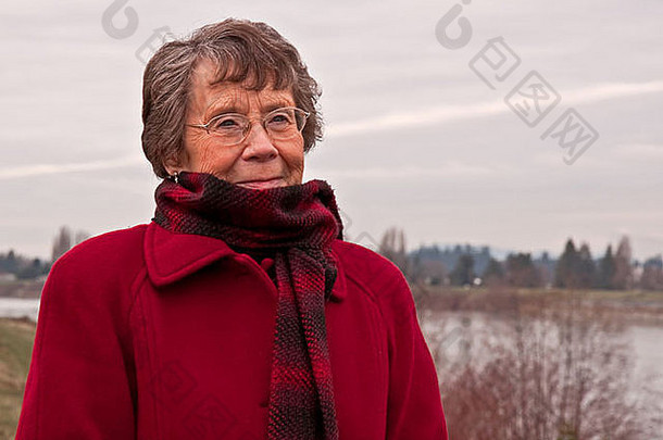 肖像高加索人高级公民夫人站冷她是穿红色的羊毛外套格子红色的围巾