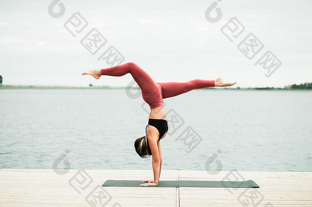 年轻的女孩瑜伽在户外码头湖她是穿黑色的前红色的紧身裤