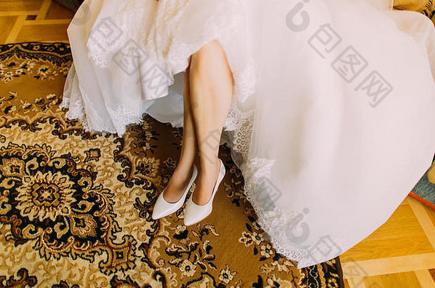 新娘优雅的白色衣服显示时尚的鞋子坐着东方风格地毯脚背景