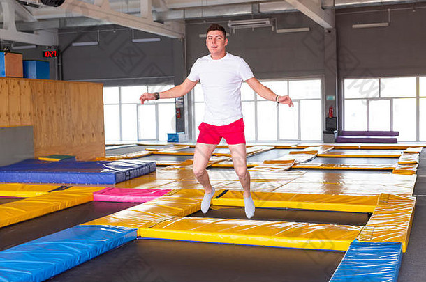 健身有趣的休闲体育运动活动概念英俊的快乐男人。跳蹦床在室内