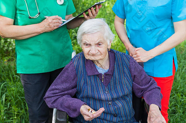上了年纪的生病的女人轮椅医疗护士讨论治疗户外