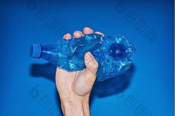 手挤压塑料瓶蓝色的背景浪费消费减少塑料概念最小的闪光摄影直接闪光复制空间