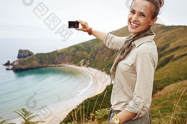 野生西班牙肖像微笑活跃的女人徒步旅行者采取照片数字相机前面海洋视图景观