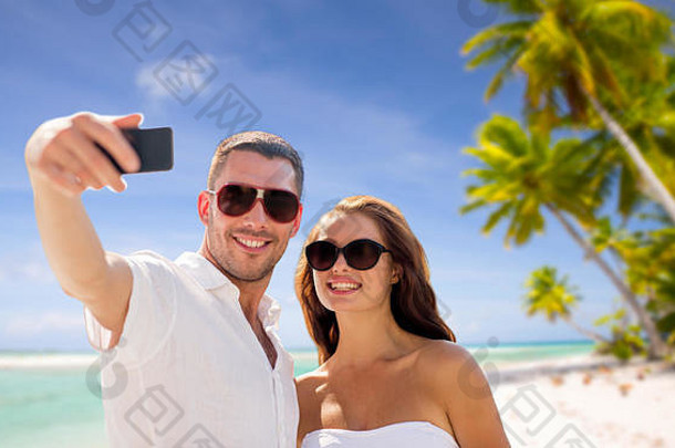 夫妇使自拍智能手机海滩