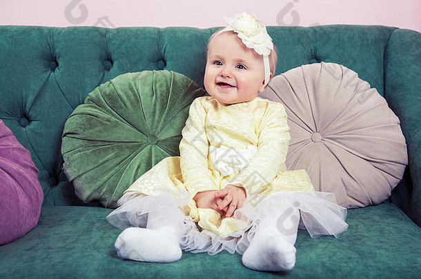 美丽的金发女郎小女孩黄色的衣服花头坐着绿色沙发相机