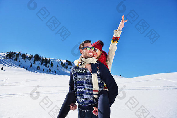 年轻的夫妇有趣的雪快乐男人。山给肩扛骑微笑女朋友