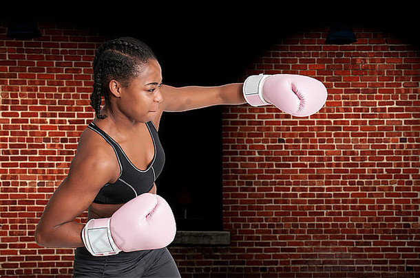 美丽的年轻的黑色的女人穿一对拳击手套