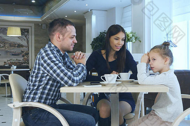快乐年轻的父母聊天witn女儿家庭假期咖啡馆喝茶