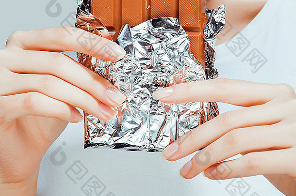 女人吃巧克力关闭手修指甲法国指甲持有糖果美丽的手指
