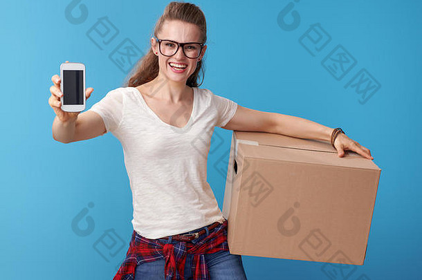 微笑年轻的女人白色衬衫纸板盒子显示手机空白屏幕蓝色的背景