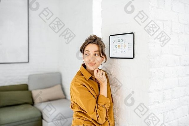 肖像快乐年轻的女人控制首页数字触摸屏幕面板安装墙生活房间
