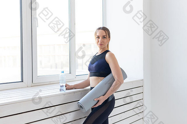 瑜伽健康的体育运动概念年轻的适合女人持有灰色席瓶水