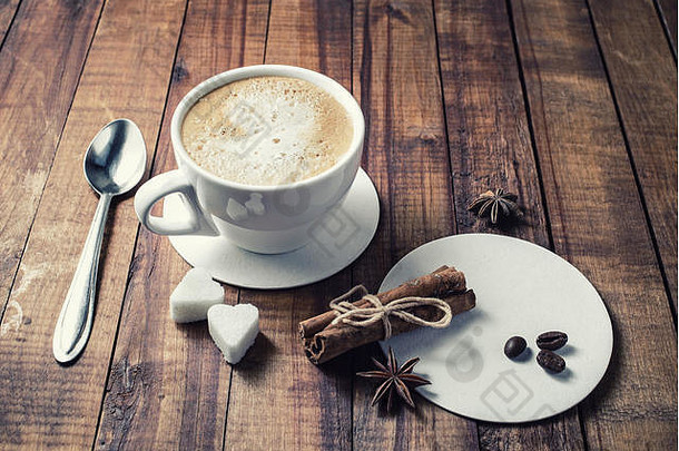 美味的新鲜的咖啡咖啡杯肉桂棒咖啡豆子茴香糖勺子杯垫古董木厨房表格背景
