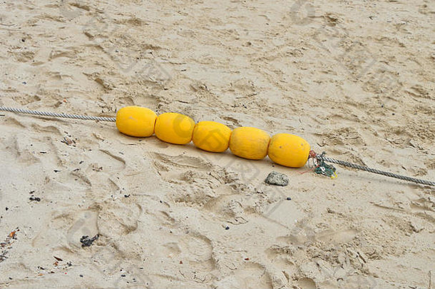 黄色的聚苯乙烯海标记浮标集团电缆拖湿沙子海海滩