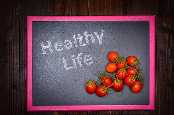图片黑板上左一边写健康的生活一边樱桃番茄木后台