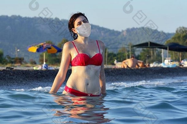 年轻的高加索人女人穿保护脸面具夏天假期海边度假胜地纤细的白色女游泳海