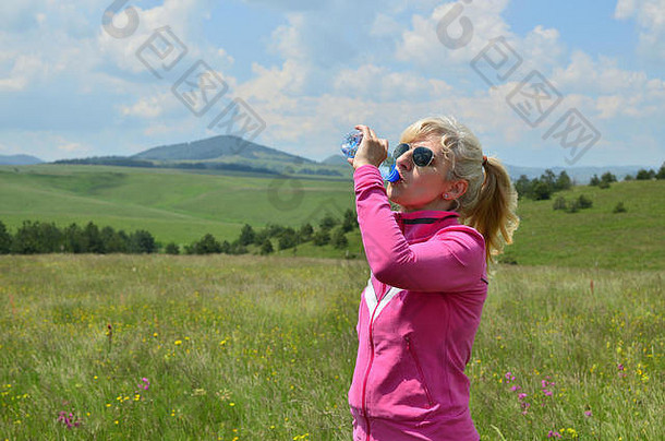 女人穿着体育运动衣服喝水塑料瓶风景如画的景观