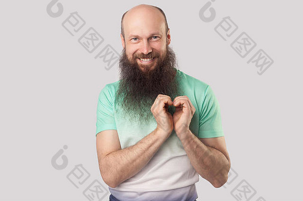 肖像快乐爱中间岁的秃男人。长胡子绿色t恤站心形状相机露出牙齿的微笑在