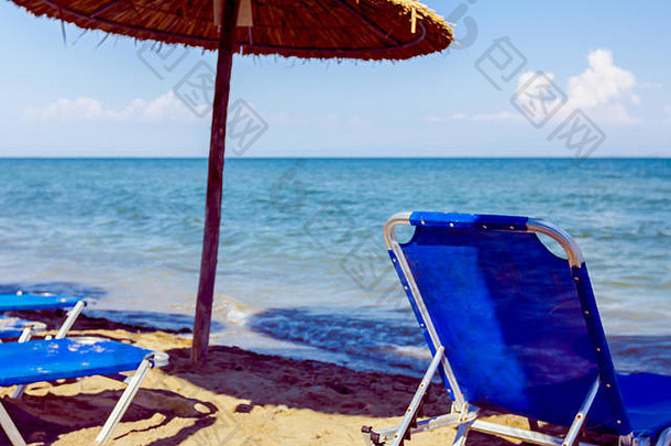 视图空公共海滩茅草遮阳篷雨伞塑料躺椅完美的假期