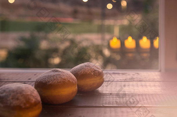 生活犹太人假期光明节甜甜圈烛光反射窗口浅景深光明节庆祝活动概念