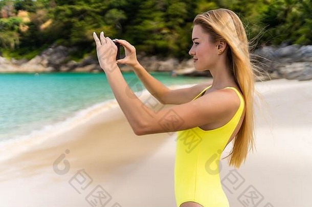 回来视图女人采取照片聪明的电话相机海滩