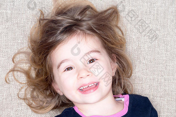漂亮的活泼的一年女孩说谎地毯头发飞行脸微笑幸福的有点