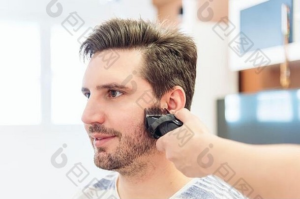 女人切割头发年轻的男人。临时搭建的理发师的首页检疫概念