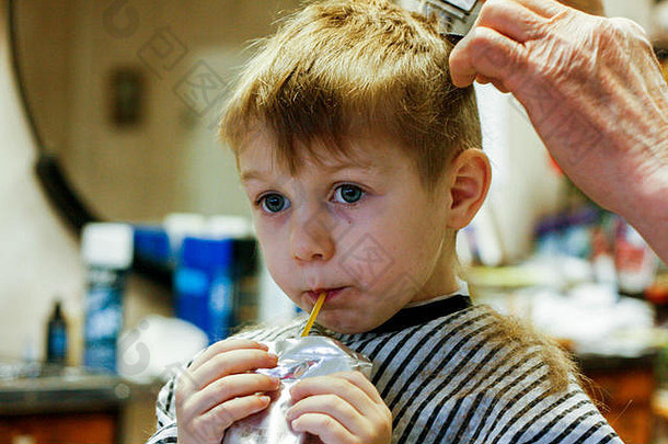 年轻的男孩喝汁盒子头发减少理发师