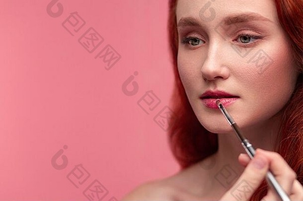 化妆艺术家适用于口红手化妆主绘画嘴唇年轻的红色头发的人女孩肖像美丽的健康的女孩清洁皮肤