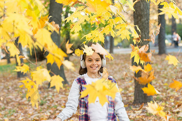 旋律秋天下降叶子快乐女孩穿耳机秋天景观可爱的孩子微笑立体声耳机小孩子听现代耳机耳机技术