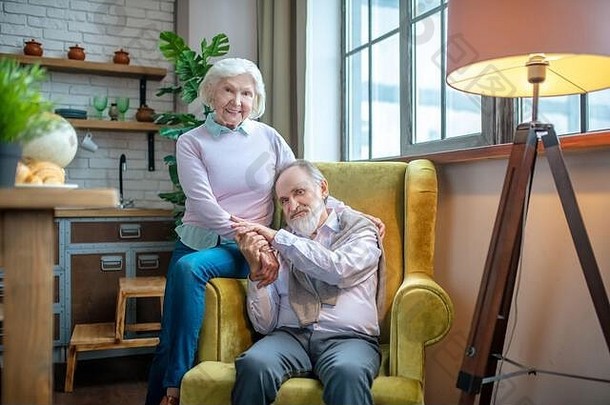 可爱的上了年纪的夫妇坐着黄色的扶手椅