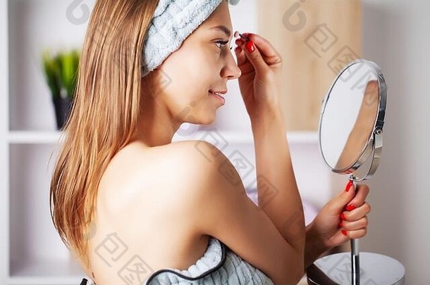 美化妆年轻的女人美丽的皮肤持有睫毛刷眼睛