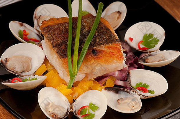 脆烤鳕鱼角床上细香葱新装的蛤蜊蛤辣椒黑色的板