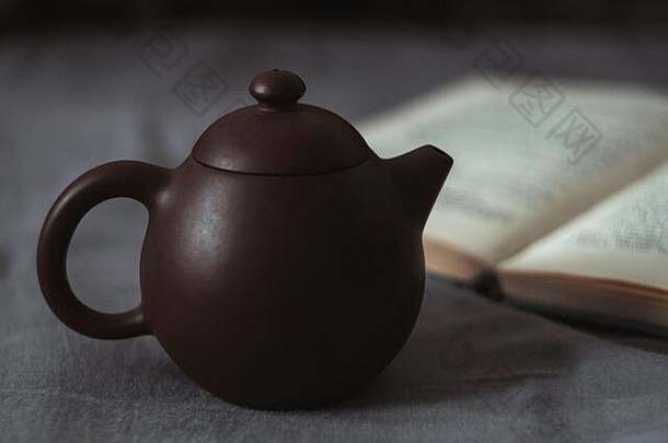 黑暗软特写镜头图片小棕色（的）粘土茶壶开放纸书灰色的布覆盖表面