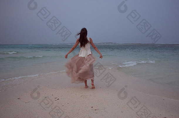 回来视图年轻的女人海地平线浅黑肤色的女人女孩白色裙子飞行风背景海