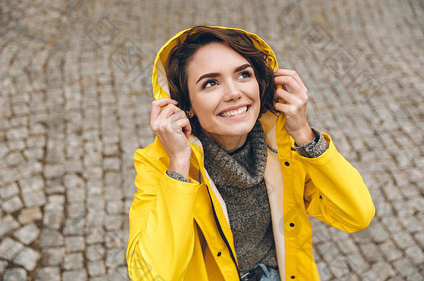 高加索人可爱的女黄色的外套穿罩向上欢乐多雨的天气走城市中心