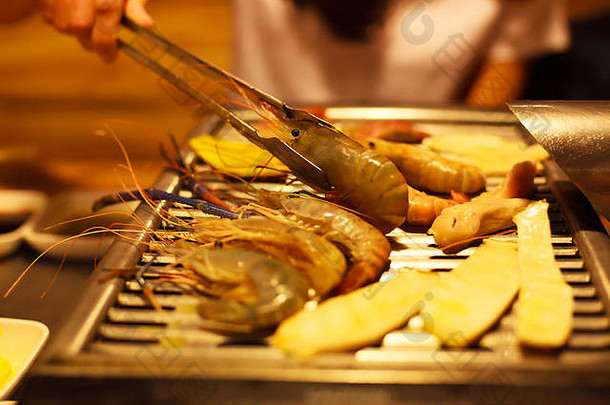 女人手持有不锈钢钢热食物引人入胜的舌夹煎肉蔬菜食物烧烤烧烤锅