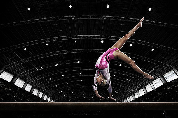 年轻的女人体操运动员执行梁平衡手狭窄的一块装置