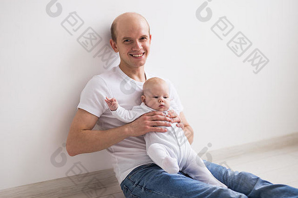 孩子们家庭为父之道概念快乐秃父亲持有婴儿女儿膝盖白色背景
