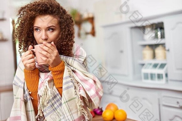 年轻的女人包装毯子喝热茶
