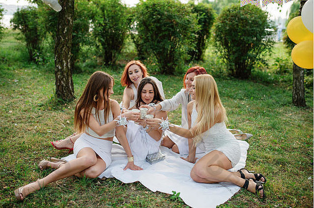 女孩香槟手穿白色衣服母鸡聚会，派对坐着户外公园有趣的