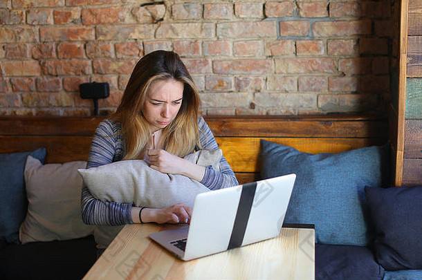年轻的女人坐着舒适的咖啡房子表格玻璃杯卡布奇诺咖啡聊天移动PC