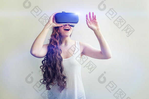 微笑年轻的女人穿虚拟现实眼镜头盔耳机白色背景智能手机虚拟现实护目镜技术模拟高新技术电子游戏概念