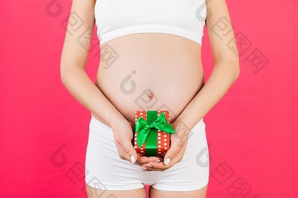 裁剪图像怀孕了女人持有礼物盒子肚子粉红色的背景期待婴儿复制空间