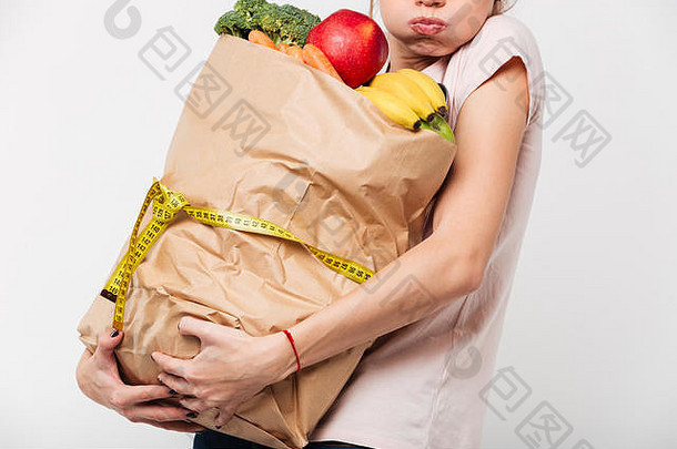 关闭女人持有重袋食品杂货包装测量磁带孤立的白色背景