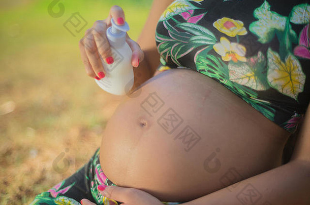怀孕了女人公园把奶油肚子避免拉伸标志着