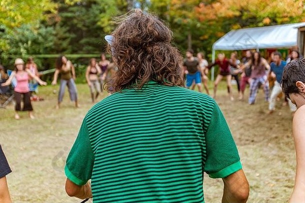 波西米亚男人。波浪肩膀长度浅黑肤色的女人头发浅焦点穿绿色条纹衬衫多元文化的节日