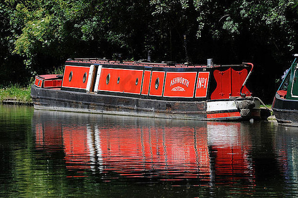 明亮的红色的narrowboat停泊树大联盟运河