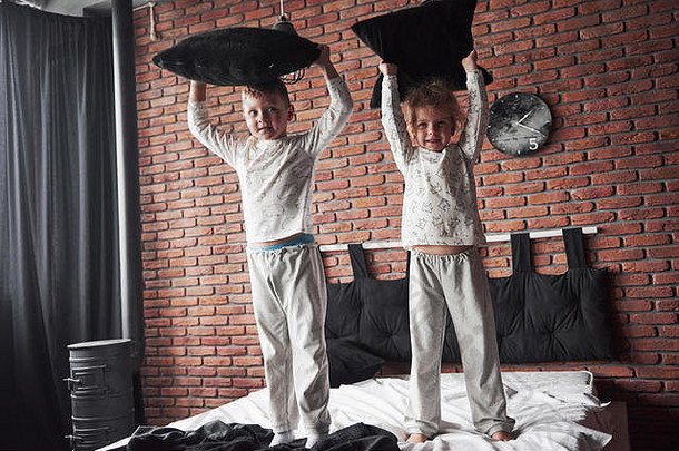 淘气的孩子们男孩女孩上演了枕头战斗床上卧室种类游戏